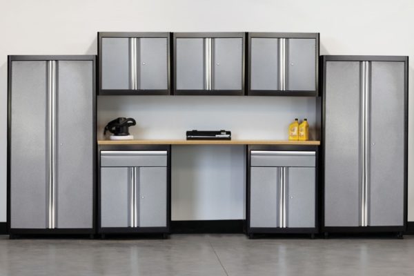 Light-industrial storage cabinets with graphite powdercoat cases and ribbed stainless steel door accents, integrated with light-duty low height work bench finished with a butcher block top surface.