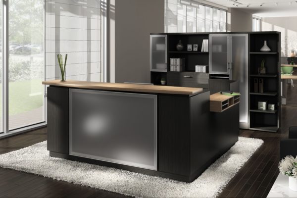 Espresso reception desk with return, glass front panel, aluminum-accented rear storage, paper management, and medium cherry accents.