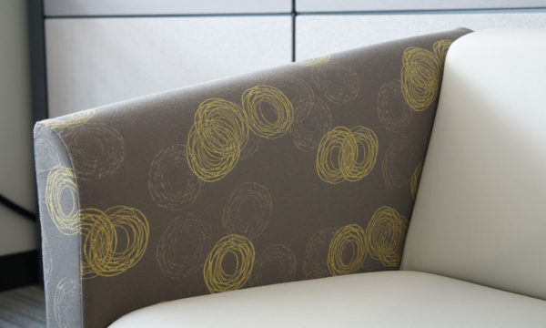 Arm detail of contemporary two-tone club chair in medium grey and cream-colored fabrics.