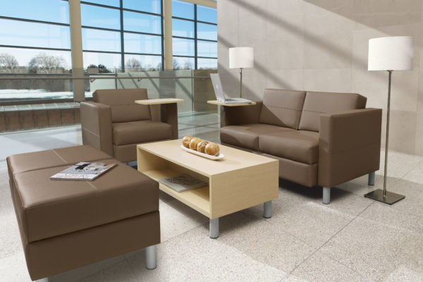 Transitional waiting room furniture including loveseat and chair, integrated maple laminated writing tablets, matching brown leather ottoman, and matching maple coffee table with tungsten feet.